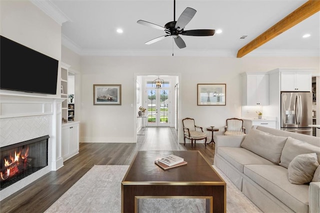 living area featuring ornamental molding, a tile fireplace, ceiling fan, and wood finished floors