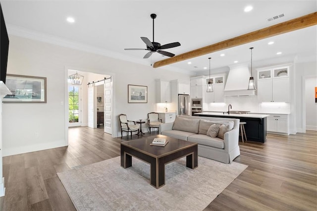 living area featuring recessed lighting, a barn door, ceiling fan, light wood finished floors, and visible vents
