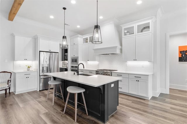 kitchen featuring a breakfast bar area, a sink, stainless steel appliances, light countertops, and a center island with sink