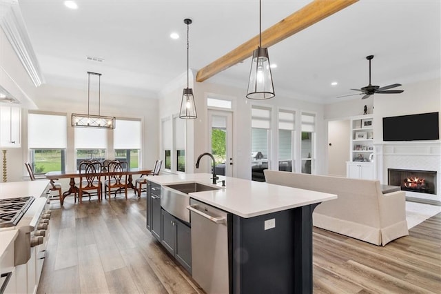 kitchen with stainless steel dishwasher, a sink, light countertops, recessed lighting, and ornamental molding