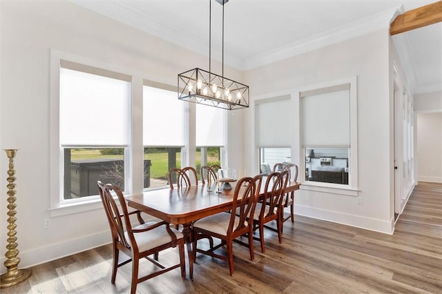 dining space featuring crown molding, a notable chandelier, wood finished floors, and baseboards