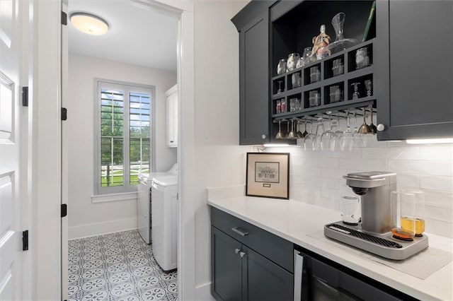 laundry area featuring beverage cooler, a bar, baseboards, washer and dryer, and cabinet space