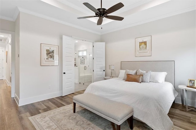 bedroom featuring wood finished floors, connected bathroom, ceiling fan, baseboards, and crown molding