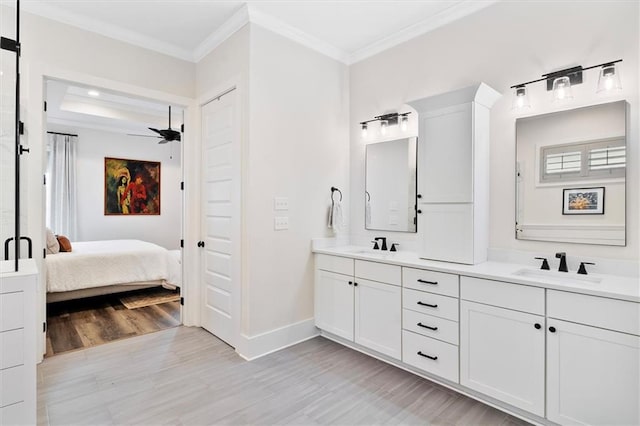 ensuite bathroom featuring connected bathroom, baseboards, ornamental molding, and a sink