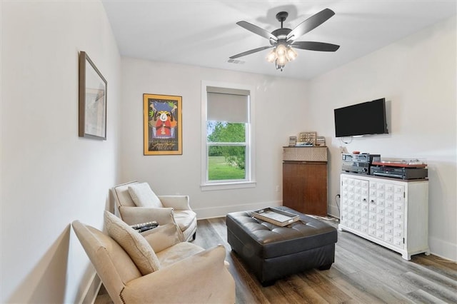 living room featuring baseboards, visible vents, wood finished floors, and a ceiling fan