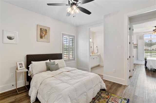 bedroom with wood finished floors, ensuite bathroom, a ceiling fan, and baseboards
