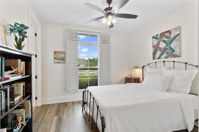 bedroom with ceiling fan, wood finished floors, and baseboards