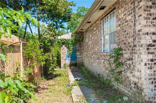 view of side of home featuring fence and brick siding