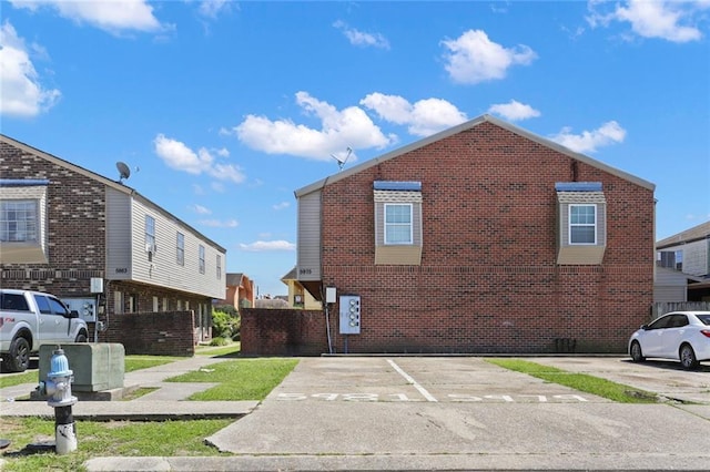 view of side of property featuring uncovered parking and brick siding