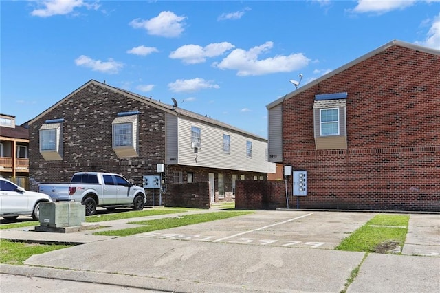 exterior space with uncovered parking and brick siding