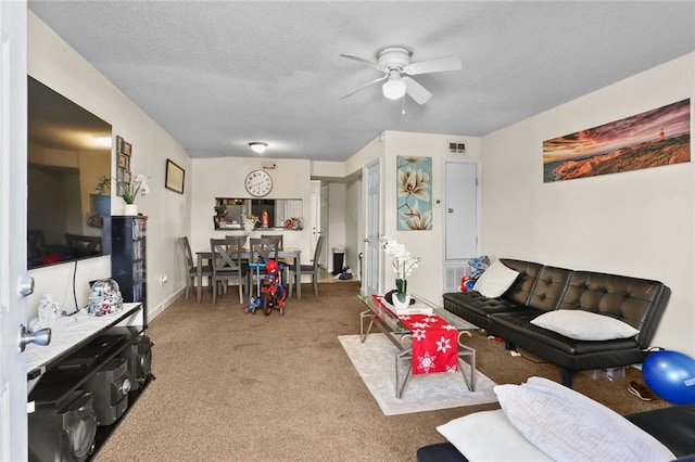 living room with baseboards, a ceiling fan, a textured ceiling, and carpet
