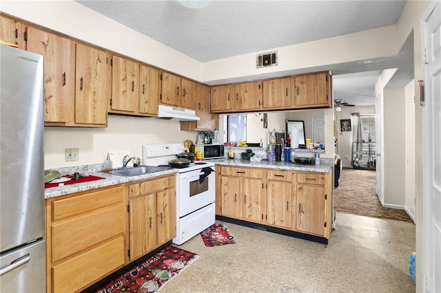 kitchen featuring a sink, under cabinet range hood, white range with electric stovetop, a peninsula, and freestanding refrigerator