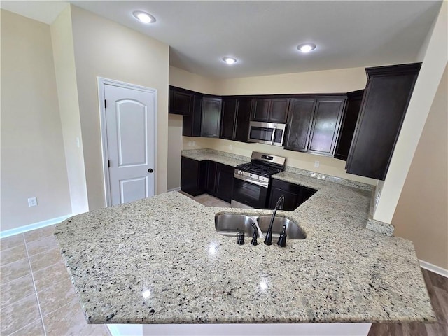 1012 Berkshire Dr, Pearl River, LA 70452 - kitchen with a sink, stainless steel appliances, a peninsula, light stone counters, and baseboards