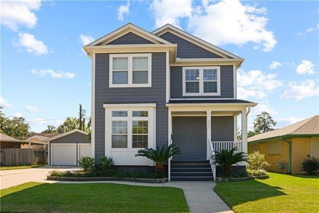 view of front of house featuring a porch, a front lawn, an outdoor structure, a detached garage, and fence