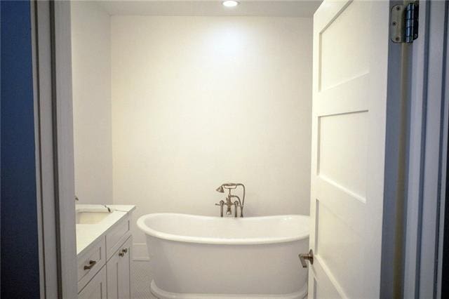 full bathroom with a soaking tub, recessed lighting, and vanity