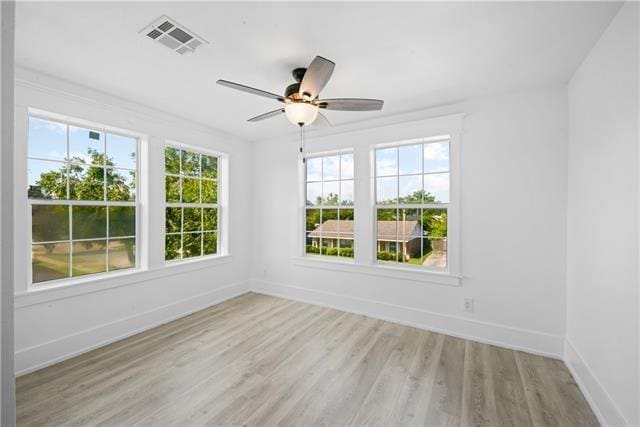 empty room featuring baseboards, visible vents, wood finished floors, and ceiling fan