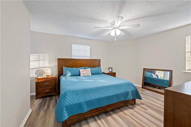bedroom with a textured ceiling, wood finished floors, a ceiling fan, and baseboards