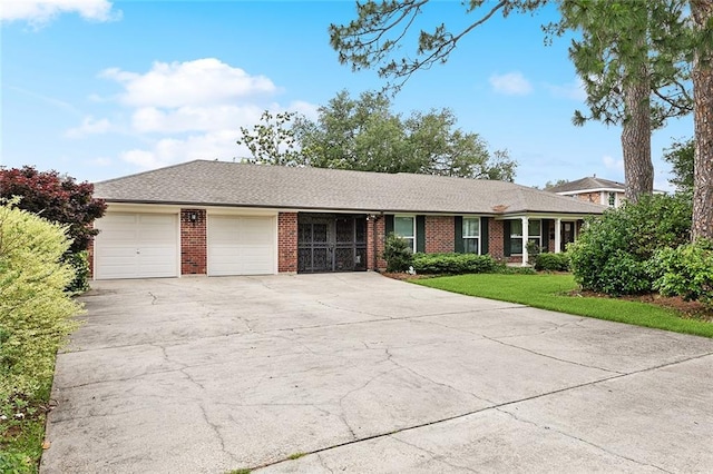 ranch-style home featuring concrete driveway, a front yard, brick siding, and a garage