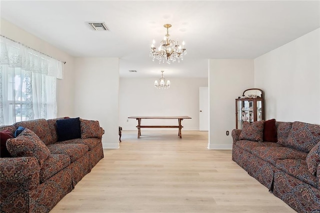 living room with a chandelier, visible vents, light wood-style floors, and baseboards