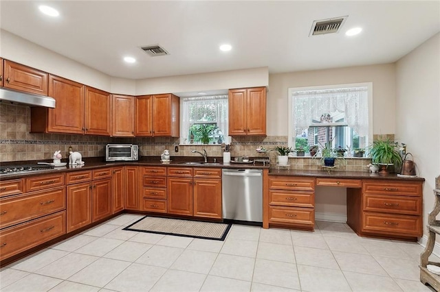kitchen with visible vents, stainless steel dishwasher, under cabinet range hood, and a sink