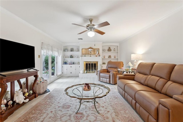 living area featuring visible vents, light wood finished floors, ornamental molding, a brick fireplace, and a ceiling fan