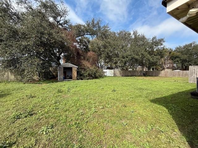 view of yard with fence, a storage unit, and an outdoor structure