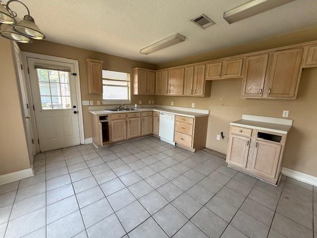 kitchen with white dishwasher, a textured ceiling, visible vents, and light tile patterned flooring