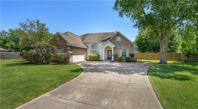 view of front facade with concrete driveway, a front yard, an attached garage, and fence