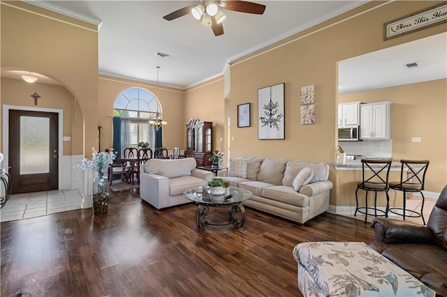 living room with visible vents, wood finished floors, ceiling fan with notable chandelier, and ornamental molding
