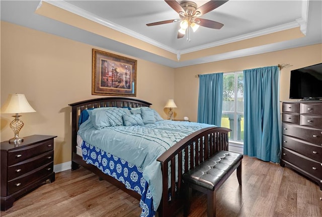 bedroom with crown molding, wood finished floors, and a tray ceiling