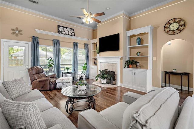 living room with a tile fireplace, wood finished floors, plenty of natural light, and a ceiling fan