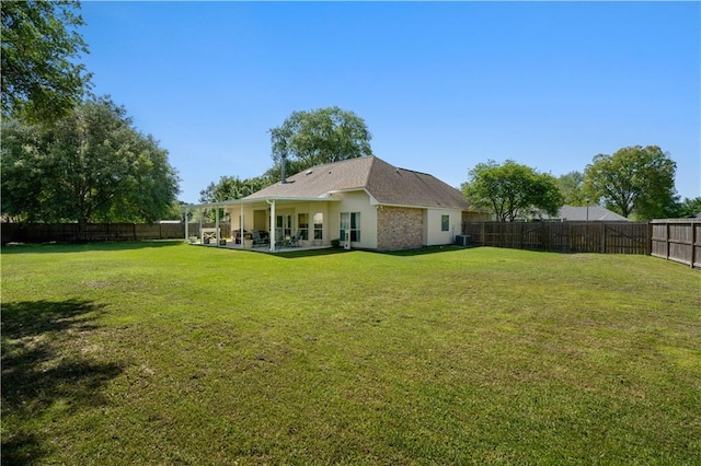 rear view of house with a lawn, a fenced backyard, and a patio area