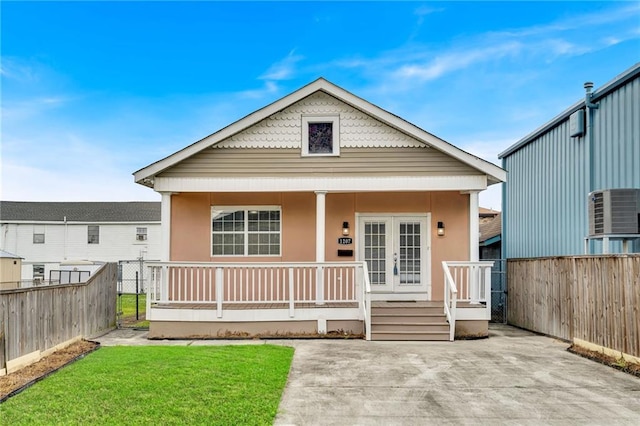 view of front facade featuring a porch, a front yard, cooling unit, and fence
