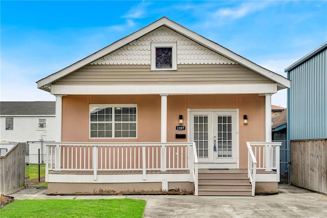 bungalow with fence, a porch, and stucco siding