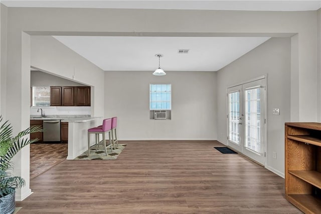 unfurnished dining area with wood finished floors, a healthy amount of sunlight, visible vents, and baseboards