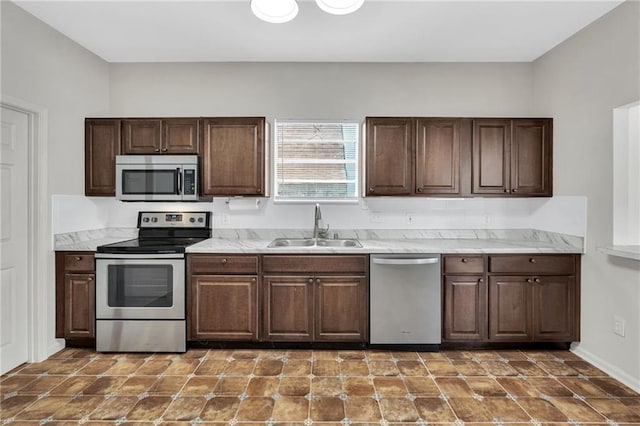 kitchen featuring dark brown cabinets, stainless steel appliances, light countertops, and a sink