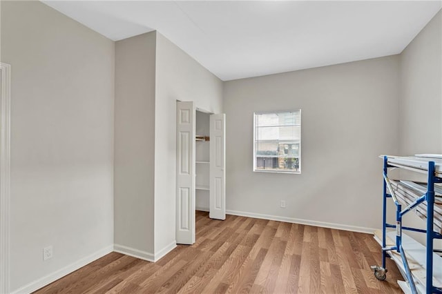 unfurnished bedroom featuring wood finished floors and baseboards