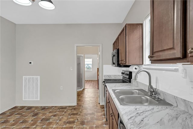 kitchen with light countertops, a sink, baseboards, visible vents, and stainless steel electric stove