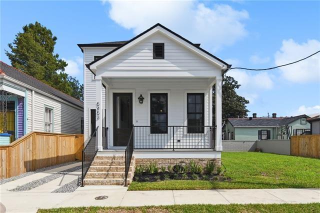 shotgun-style home with covered porch, fence, and a front yard