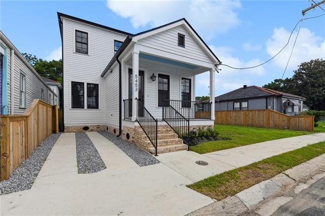 shotgun-style home featuring fence, a porch, and a front lawn