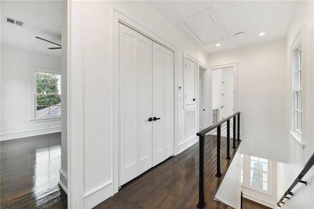 corridor with an upstairs landing, visible vents, attic access, dark wood-style flooring, and recessed lighting
