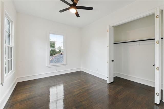 unfurnished bedroom featuring dark wood-style flooring, ceiling fan, a closet, and baseboards