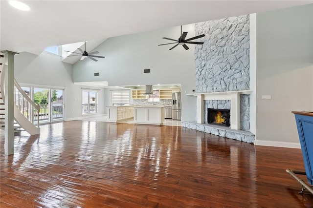 4435 Francecso Rd, New Orleans, LA 70129 - unfurnished living room featuring light wood finished floors, ceiling fan, high vaulted ceiling, a stone fireplace, and baseboards
