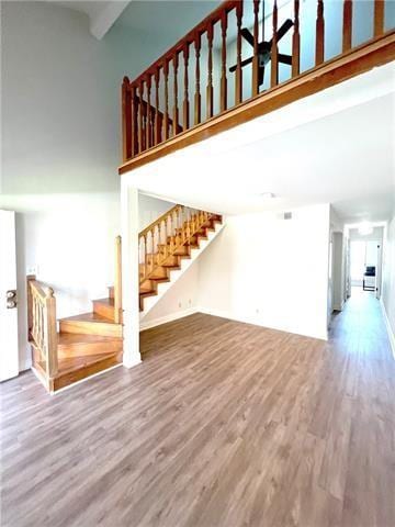 248 Cherokee St Unit 30, New Orleans, LA 70118 - unfurnished living room with a high ceiling, stairway, and wood finished floors