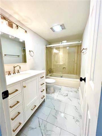 248 Cherokee St Unit 30, New Orleans, LA 70118 - bathroom with toilet, vanity, shower / bath combination with glass door, and marble finish floors