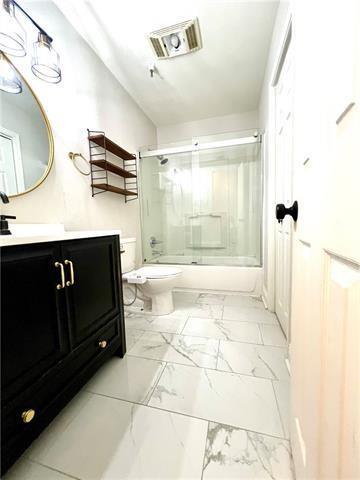 248 Cherokee St Unit 30, New Orleans, LA 70118 - bathroom featuring toilet, marble finish floors, shower / bath combination with glass door, and vanity