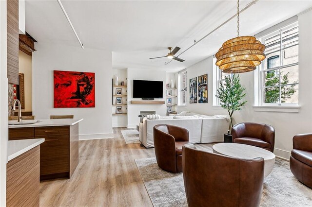 interior space with a ceiling fan, baseboards, and light wood-type flooring