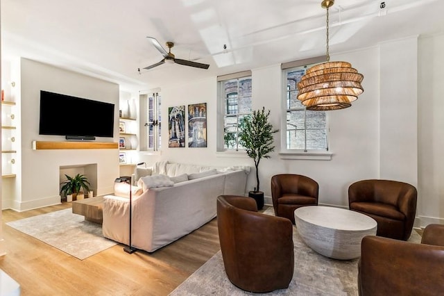 living area featuring baseboards, wood finished floors, and a ceiling fan