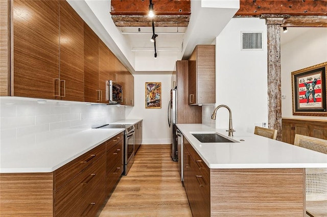 kitchen featuring modern cabinets, a sink, rail lighting, and stainless steel appliances