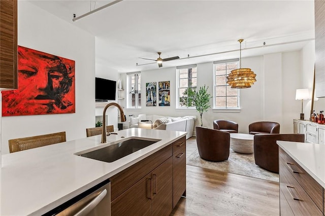 kitchen with a ceiling fan, light wood finished floors, light countertops, and a sink
